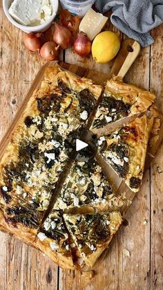 a pizza sitting on top of a wooden cutting board next to other foods and condiments