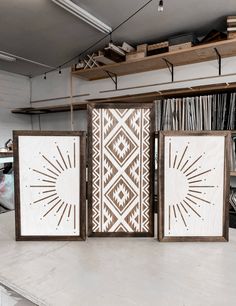 three wooden frames with designs on them in front of a bookshelf full of records