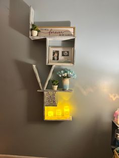 a shelf with some flowers and pictures on it next to a wall in a room