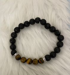 Description Embrace the volcanic vibes with of lava Stone & Tiger Eye Beaded Bracelet. The stretchy design allows for comfort and ease of wear. The 8mm volcanic stone beads and tiger eye center beads add a touch of natural elegance. Perfect for any eclectic jewelry lover! Details Bracelet Size:Length:(approx)7 inches (Elastic) Bead 8mm 18 black round lava beads 2 silver spacer beads 5 stiger eye beads Features One of a kind, fashion jewelry, everyday jewelry Great gift for that special girl, ann Casual Beaded Lava Stone Bracelets, Casual Hand-strung Lava Stone Beaded Bracelets, Casual Hand-strung Beaded Bracelets With Lava Stone, Casual Stretch Bracelet With 8mm Lava Stone Beads, Casual Black Beaded Lava Stone Bracelets, Casual Black Lava Stone Beaded Bracelets, Casual Lava Stone Beaded Bracelets, Casual Lava Stone Bracelet With Natural Stones, Casual Hand-strung Lava Stone Bracelets