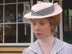 a woman wearing a white hat standing in front of a building