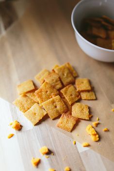 there are many pieces of crackers on the table next to a bowl and spoon