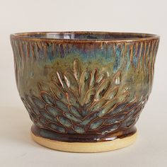 a brown and green bowl sitting on top of a table