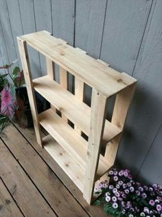 a wooden shelf sitting on top of a wooden floor next to flowers and potted plants