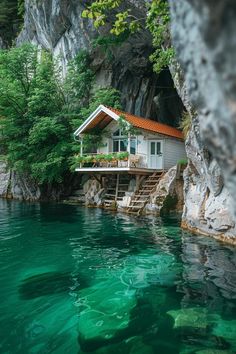 a house on the edge of a cliff next to a body of water with green algae