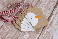 paper snowman ornament with red and white twine on wooden table top