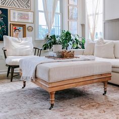 a living room filled with white furniture and lots of plants on top of the coffee table