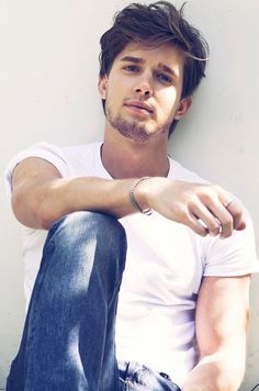 a young man sitting on the ground with his arms crossed and looking at the camera