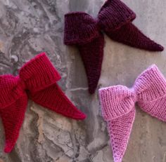 three knitted bow ties laying on top of a stone wall next to each other