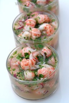 three glass containers filled with shrimp salad on top of a white countertop next to each other