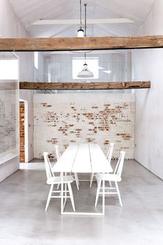 a white table and four chairs in a room with exposed brickwork on the walls