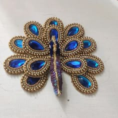 a brooch with blue and gold colored stones on it's back, sitting on a white surface