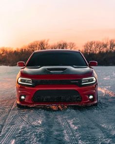 the front end of a red dodge charger on snow