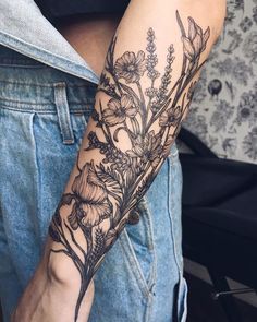 a woman's arm with flowers and leaves tattooed on the left side of her arm