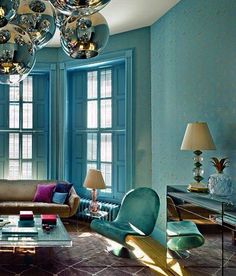 a living room filled with lots of furniture and large mirrors hanging from the ceiling above them