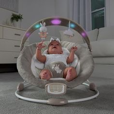 a baby laying in a swing with its hands up