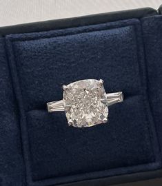 an oval diamond ring with baguetts on the sides in a velvet presentation case