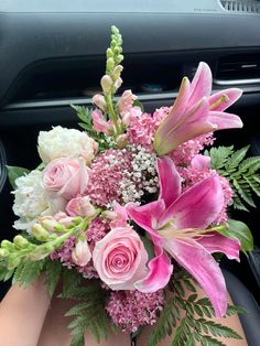 a bouquet of pink and white flowers sitting on top of a car dashboard