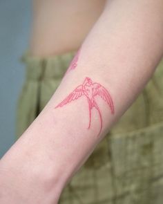 a small pink bird tattoo on the arm