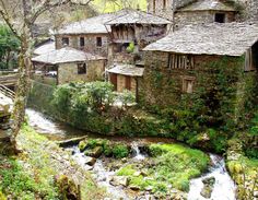 an old stone building sitting on top of a lush green hillside next to a river