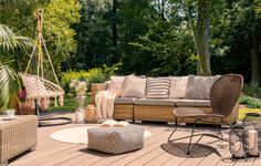 an outdoor patio with wicker furniture and plants on the deck, surrounded by greenery