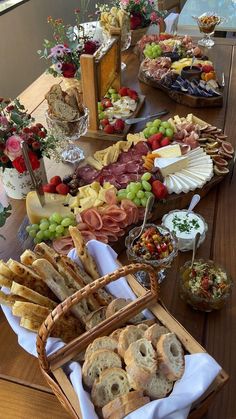 a wooden table topped with lots of different types of breads and pastries on top of it