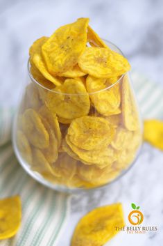 a glass bowl filled with yellow chips on top of a table