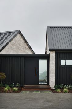 two black houses with white brick and metal roofing, one has a glass door