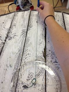 a person is using scissors to cut wood planks on a table with a circular glass plate