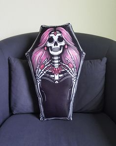 a pillow with a skeleton on it sitting on a couch in front of a wall