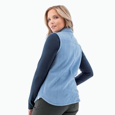 a woman is standing with her hands on her hips and looking at the camera while wearing a blue vest