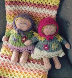 two crocheted dolls sitting on top of a blanket