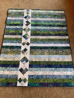 a close up of a quilt on the ground with a strip in the middle and two strips at the end