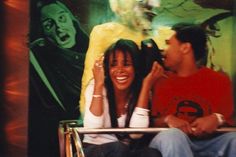 a man and woman sitting next to each other in front of a painting on the wall