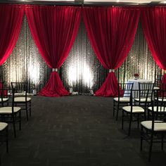 the room is decorated with red drapes and white chairs