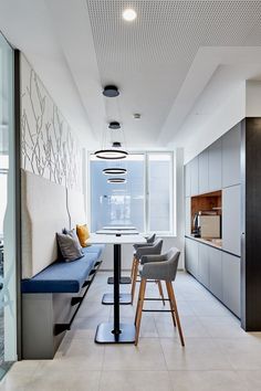 a long table and chairs in a room with white tile flooring on the walls