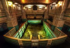 an abandoned building with green water in the center and lights on above it's doors