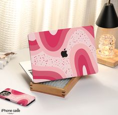 an apple laptop is sitting on top of a wooden box with pink and white designs