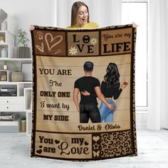 a woman holding up a blanket with the words love you are and two people on it