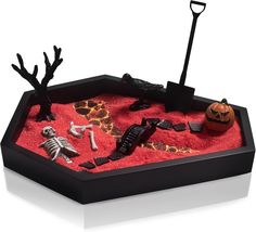 a halloween sand tray with skeletons and pumpkins