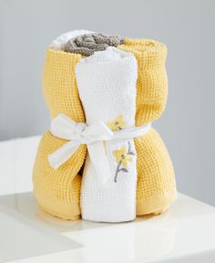 two towels wrapped in yellow and white are sitting next to each other on a table