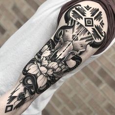 a black and white tattoo on the arm of a man with flowers in his hair