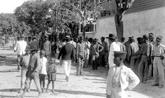 an old black and white photo of people walking down the street