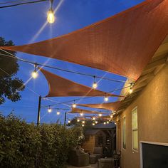 an outdoor patio covered in lights and shade sails at night with the sun shining on it