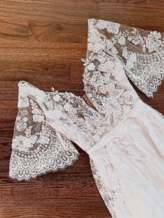 two pieces of white lace sitting on top of a wooden floor