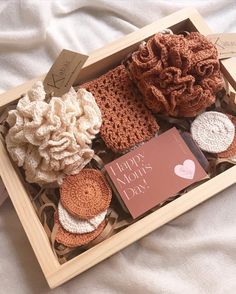 a wooden box filled with crocheted items on top of a bed