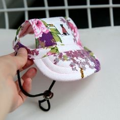 a person holding onto a hat with a lanyard on the side and flowers all over it