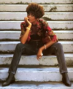 a woman sitting on some steps with her hand under her chin and looking at the camera