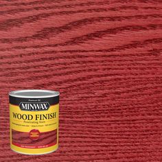 a can of wood finish sitting on top of a wooden floor next to a red wall