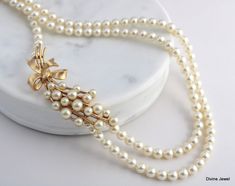 "This beautiful gold brooch necklace is perfect for your wedding day! It has cream pearls that are so elegant and perfect for your special day. This is a one of a kind necklace that will make your wedding day even more special. It has a vintage feel that will make you feel like a princess on your big day.  Necklace is strung with 6 mm Austrian pearls. Perfect for something old! **This brooch is vintage and shows typical signs of wear and age.  This is one of a kind necklace. Brooch, Trifari gold brooch with cream pearls.  Measures about 2 1/2\" by 7/8\" wide. Necklace length, Inner strand measures approximately 17\" and outer strand 18 1/2\". Finished off with a hook and eye clasp." Vintage Pearl Necklace With Pearl Charm For Anniversary, Vintage Pearl Necklace With Pearl Drop For Anniversary, Vintage Pearl Drop Necklace For Anniversary, Vintage Pearl Necklace For Anniversary, Vintage Bridal Necklace With Pearl Drop, Vintage Bridal Pearl Necklace With Pearl Drop, Elegant White Necklaces For Vintage Events, Elegant White Necklace For Vintage Events, Vintage Pearl Bridal Necklace In Pearl White